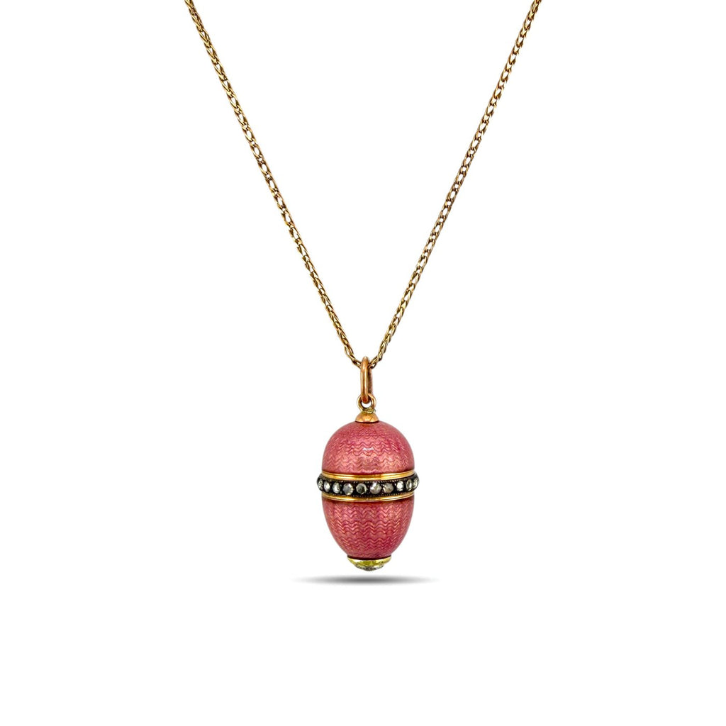 Pink enamel egg pendant with gold tone chain, topped with small round gemstone detail.