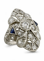 Art Deco diamond and sapphire ring with round center stone and blue side accents, platinum-tone