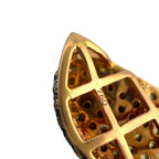 Close-up of gold charm with geometric cutout design and dark stone accents
