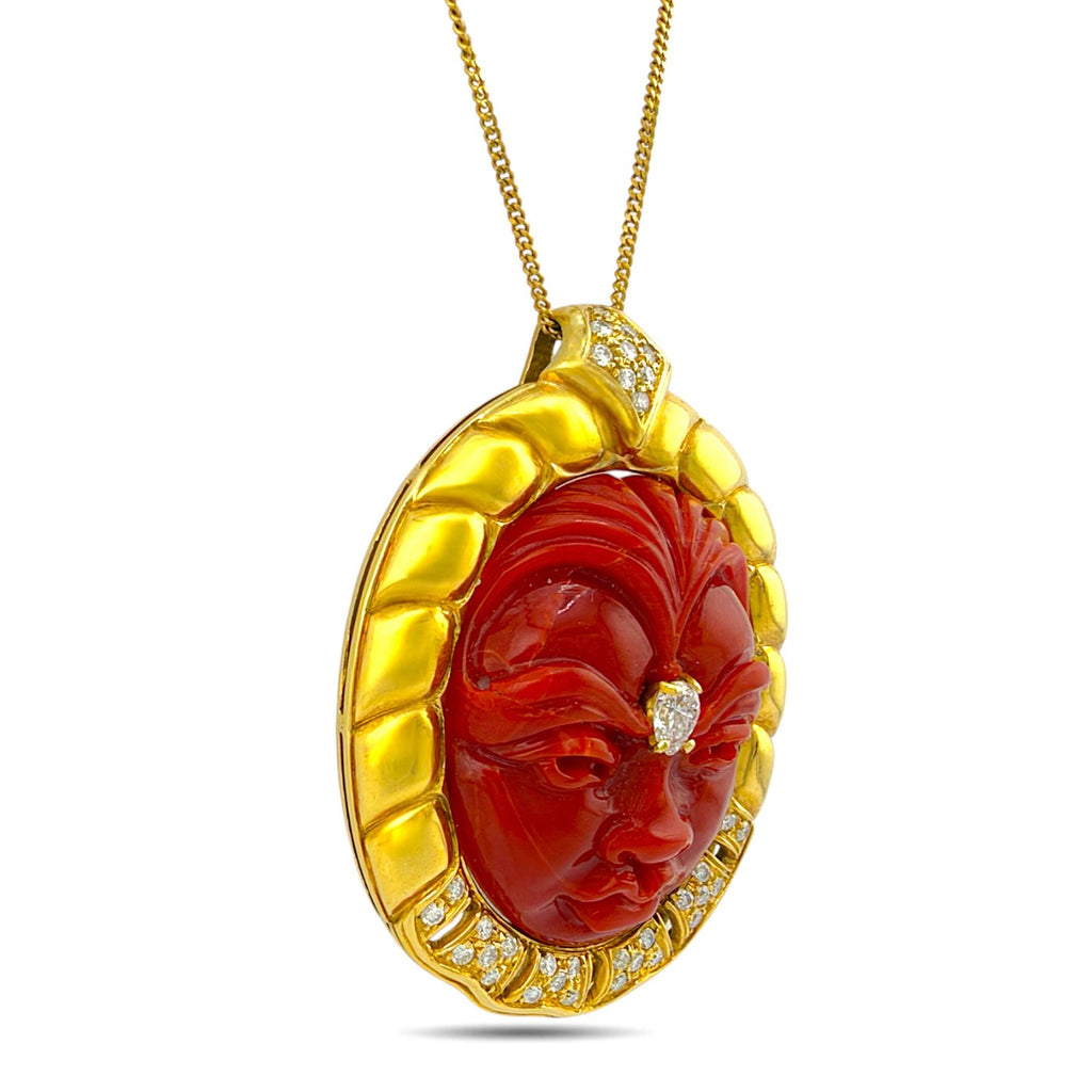 Angled view of carved coral face pendant with diamonds and gold frame