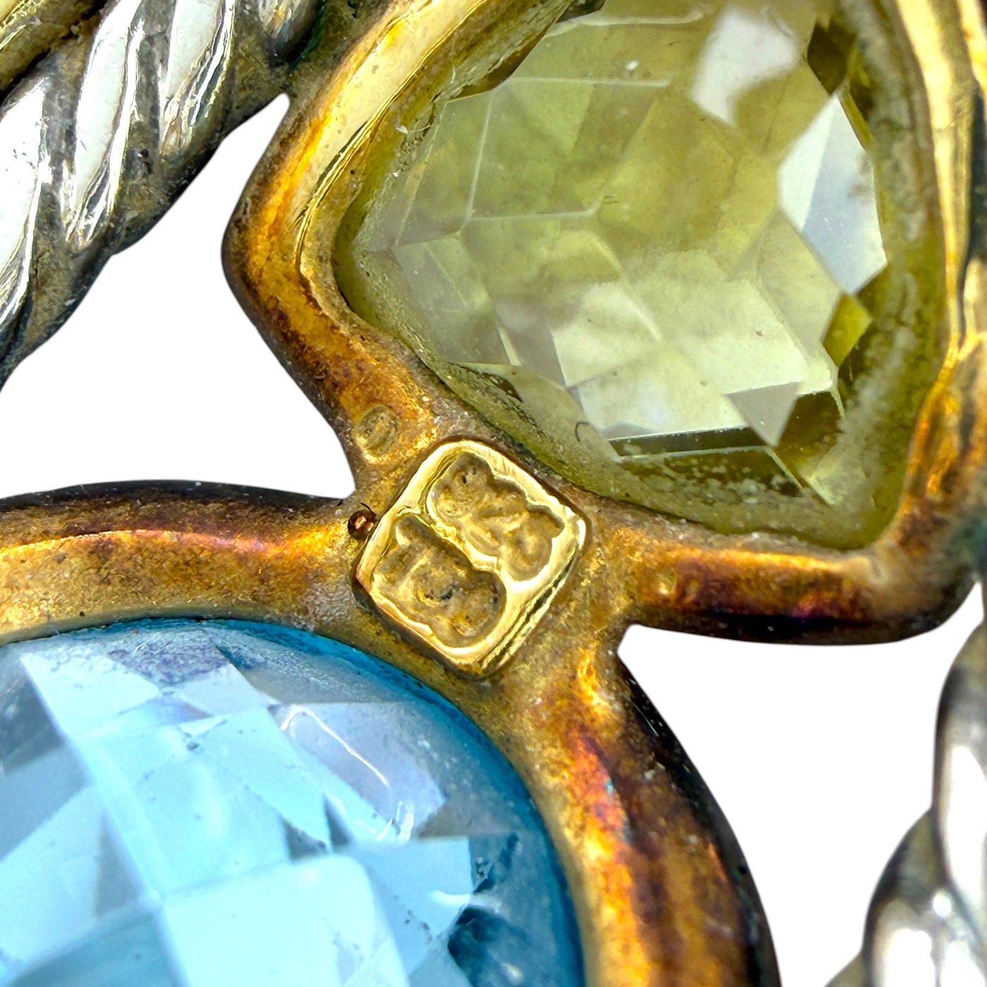 Close-up of yellow prong setting holding blue and yellow gemstones with gold detail