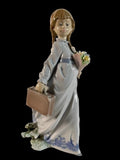 Porcelain schoolgirl figurine in white dress, holding bouquet and suitcase, blue floral trim