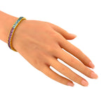 Rainbow gemstone tennis bracelet worn on the wrist, with blue and purple stones