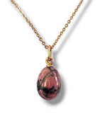 Gold chain necklace with oval pink egg pendant in ornate gold bail