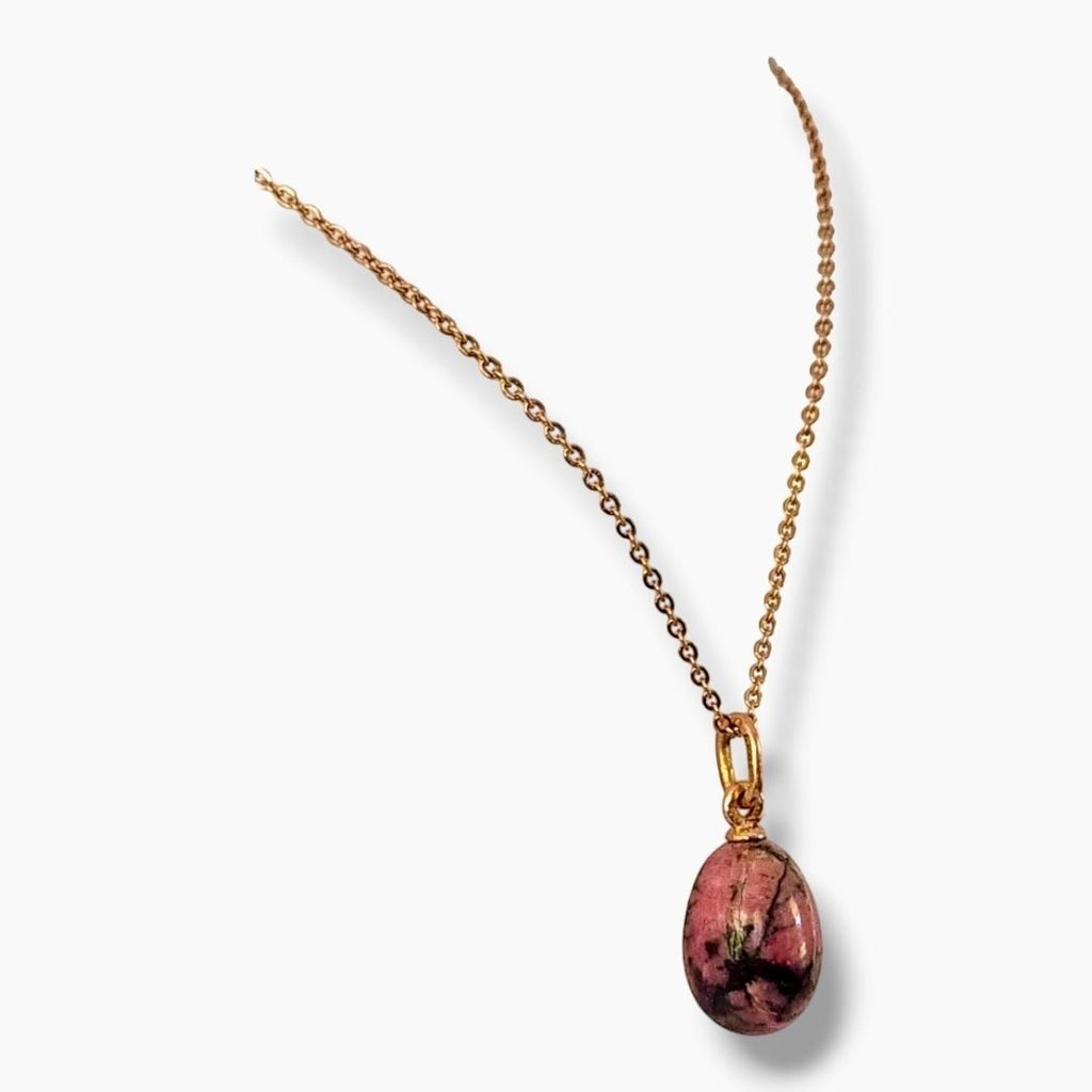 Gold chain pendant with pink oval cabochon stone framed in gold.