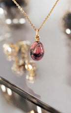 Gold pendant necklace with pink oval egg-shaped drop and glossy dark veining