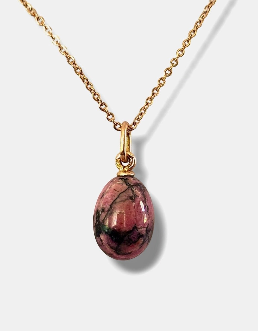 Gold chain necklace with pink oval egg pendant and round gold ring at top