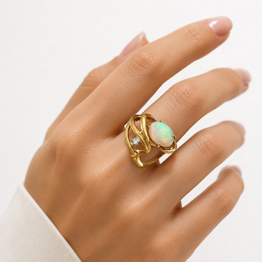 14K yellow gold opal ring on hand, oval opal with diamond side stones