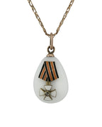 Teardrop egg pendant with striped ribbon and gold cross-flower emblem