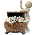 Porcelain figurine of a child holding a bouquet above an ornate flower urn