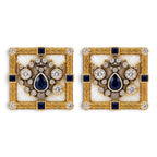 Two square gold cufflinks with blue center stone, halo of clear gems, and black accents